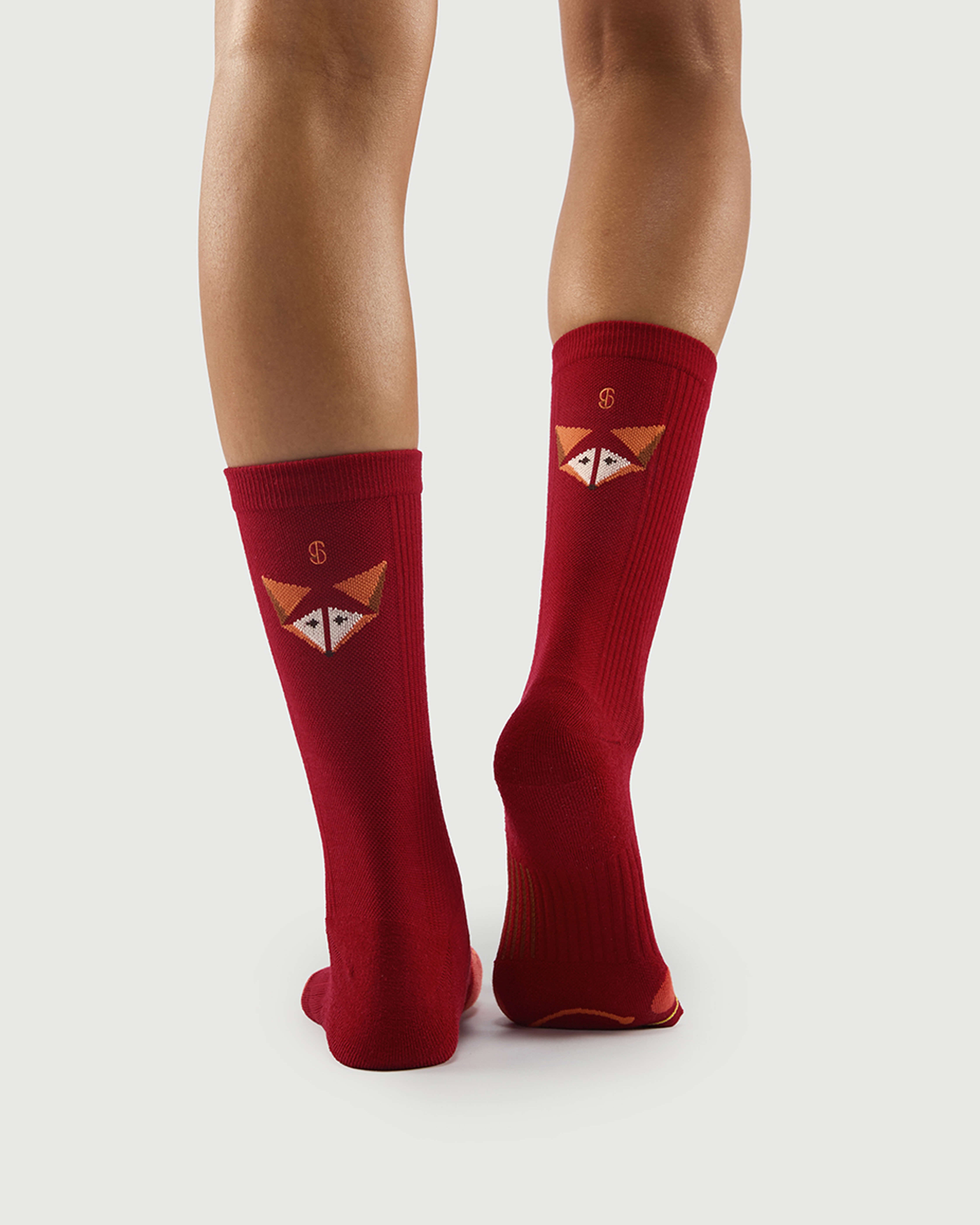 Back view of red Devoted Fox socks on a model, showing the fox face and arch support sole.