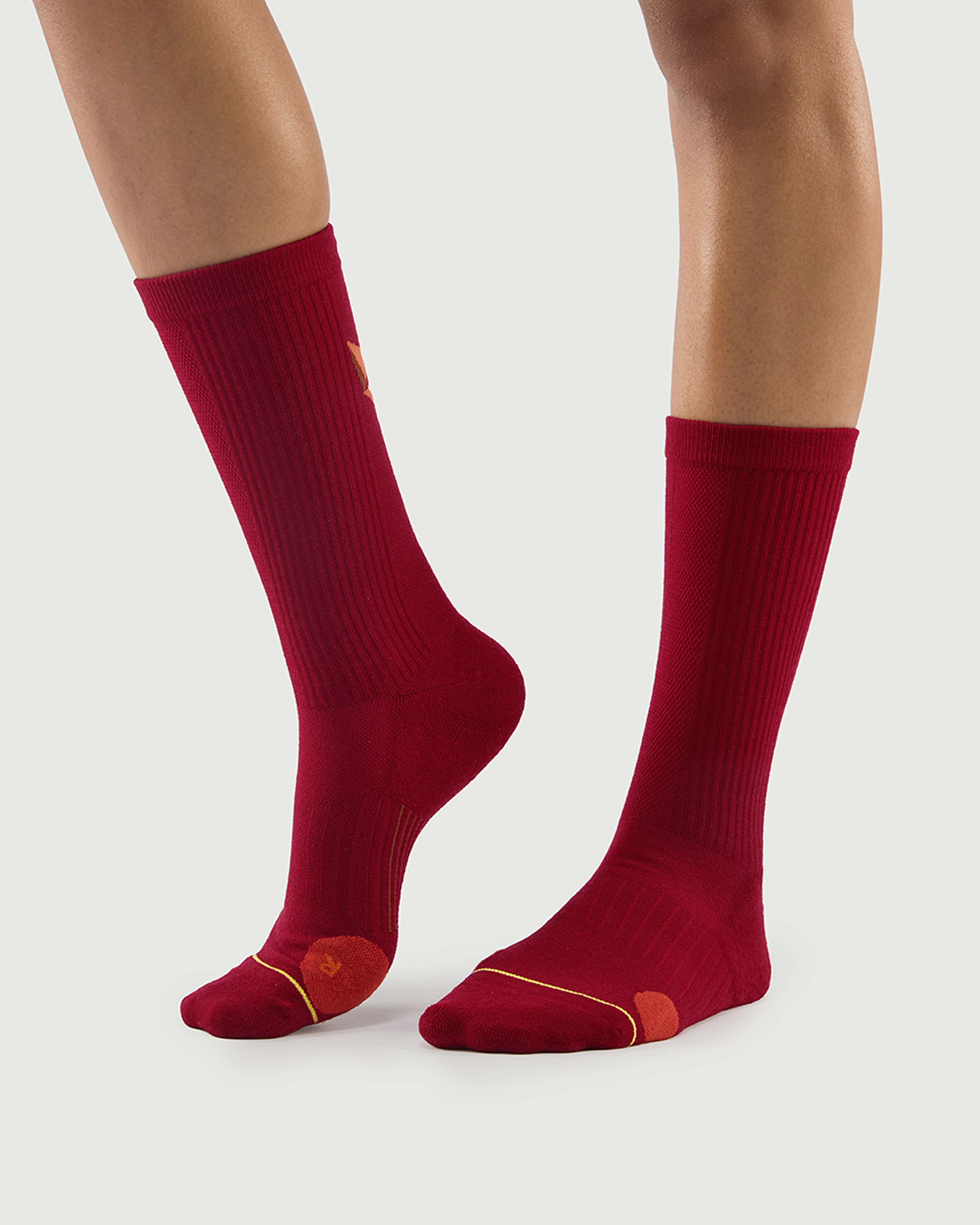 Side view of red Devoted Fox socks on a model, showcasing the protective lateral toe cushioning.