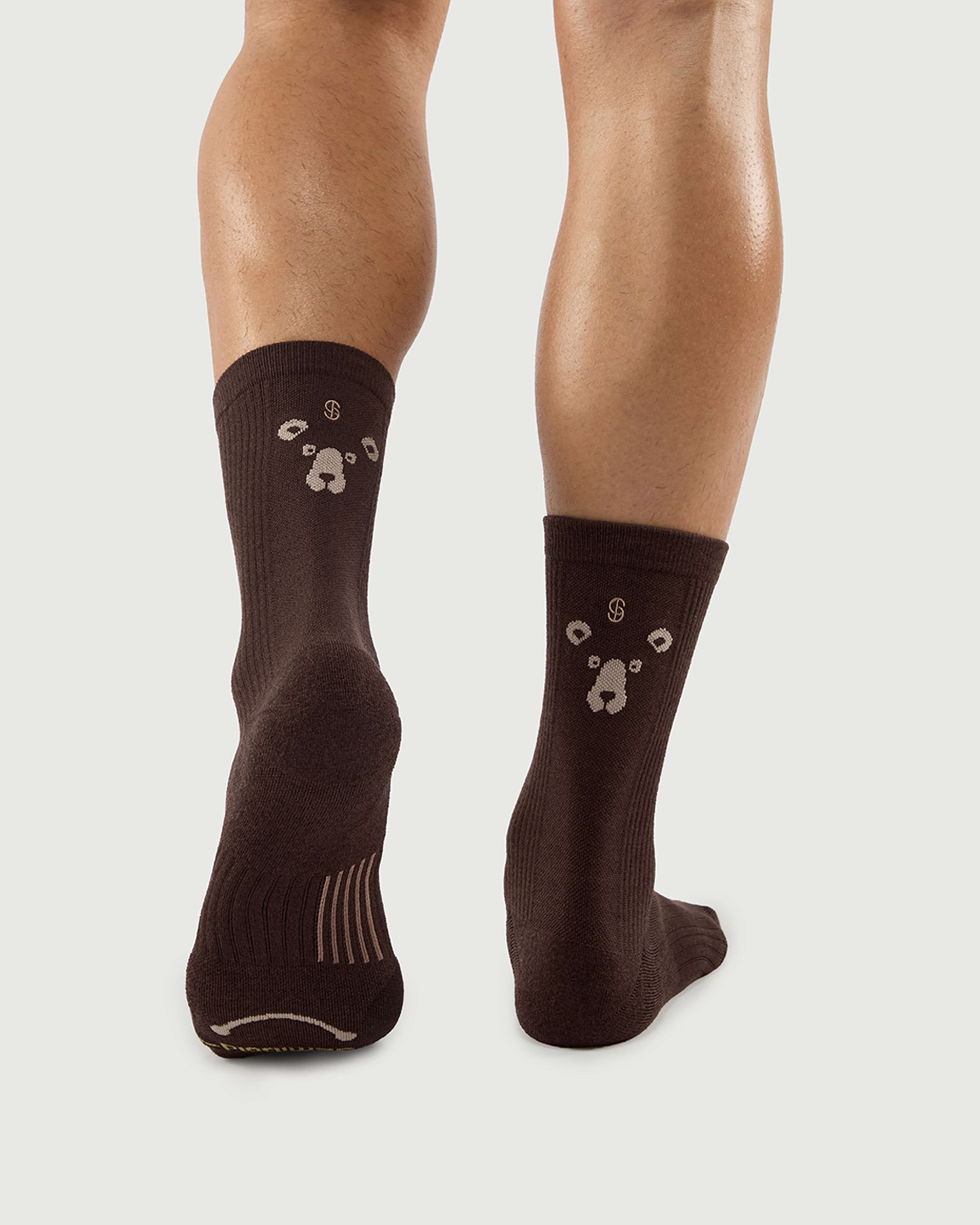 Back view of brown Humble Bear socks on a model, showcasing the bear face pattern on the heel.