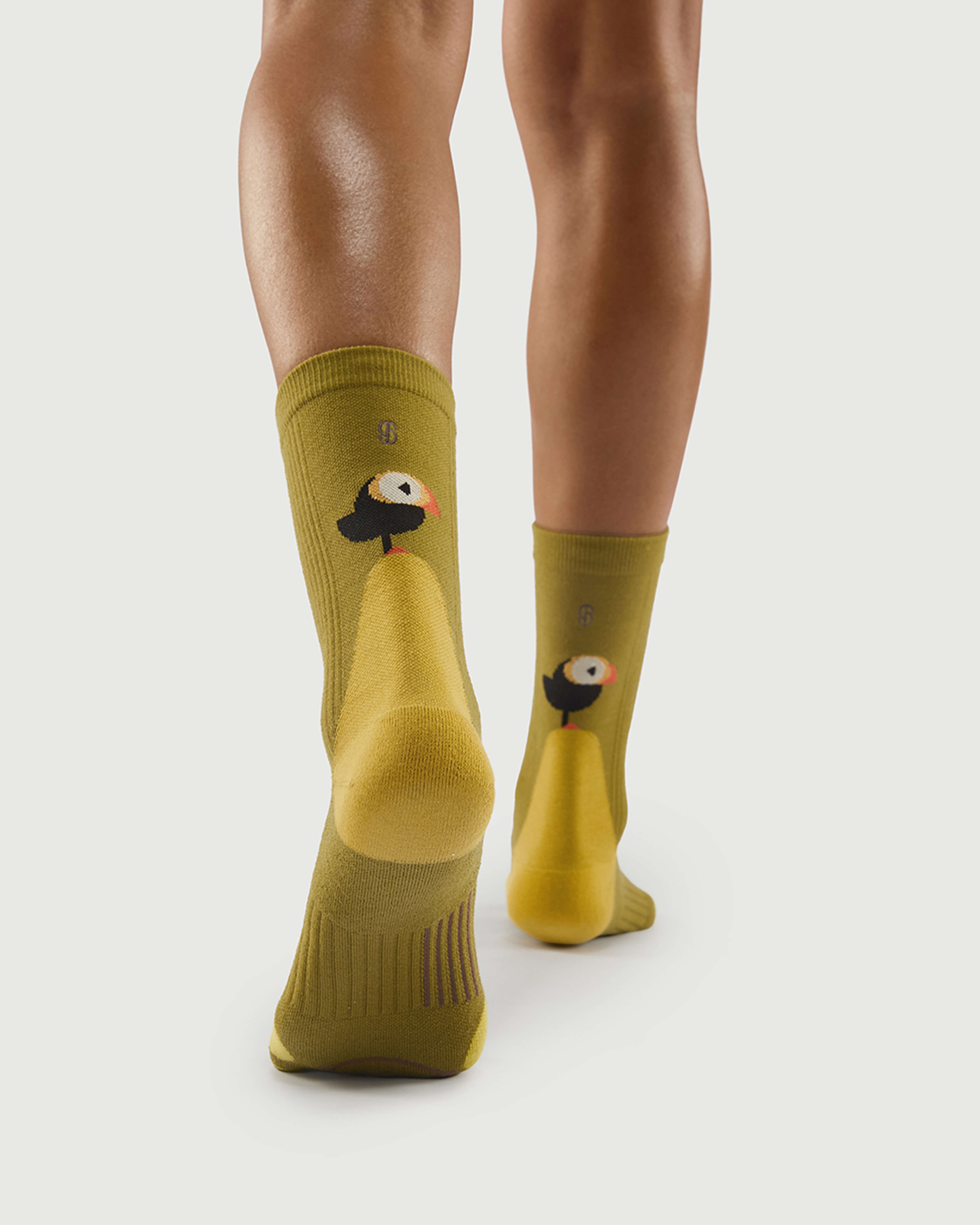 Back view of yellow Royal Puffin socks on a model, showing the puffin character and arch support.