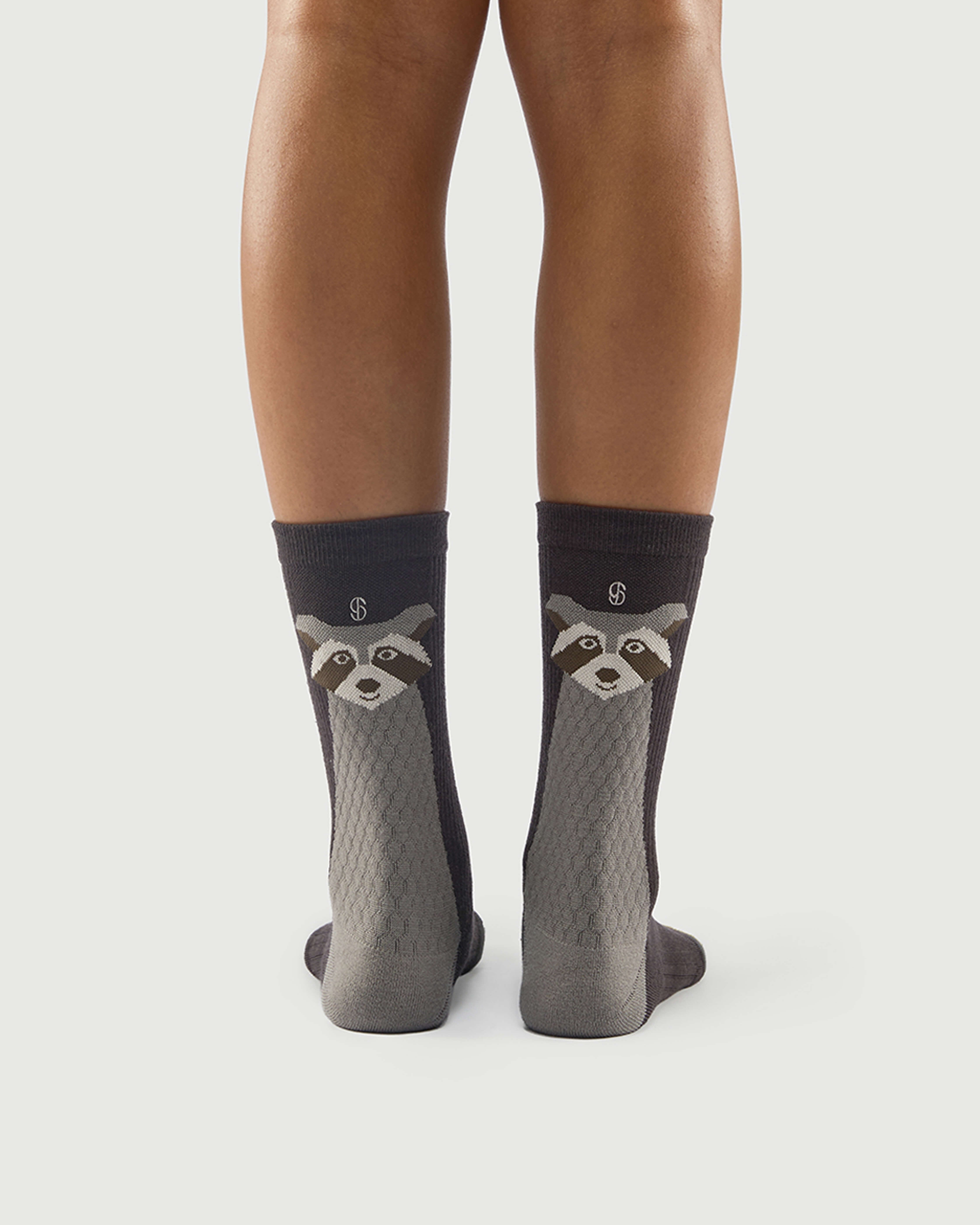 Model wearing grey and black Scrubby Raccoon socks, highlighting the raccoon character on the back.