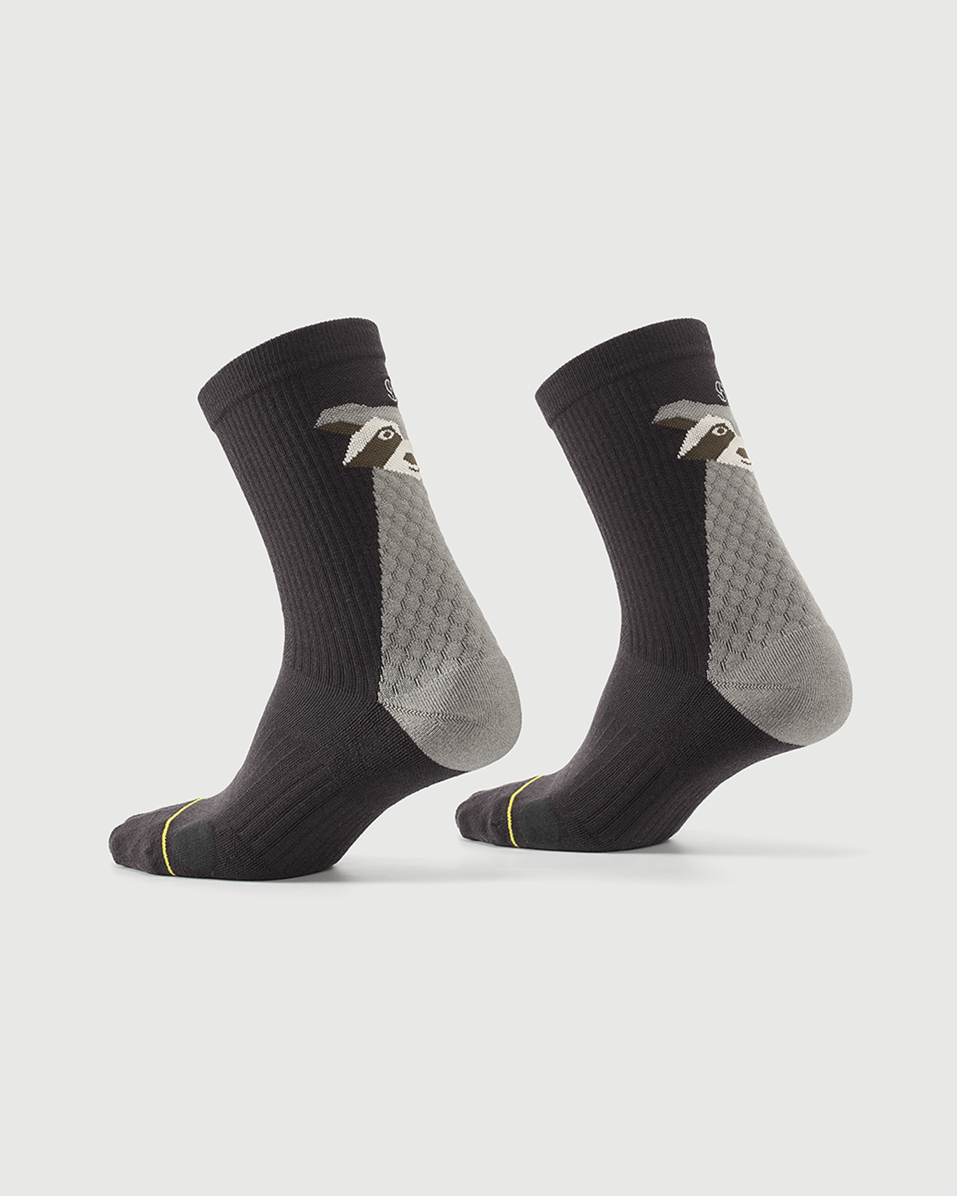 Grey Scrubby Raccoon socks on a foot form, displaying the side and rear character design.