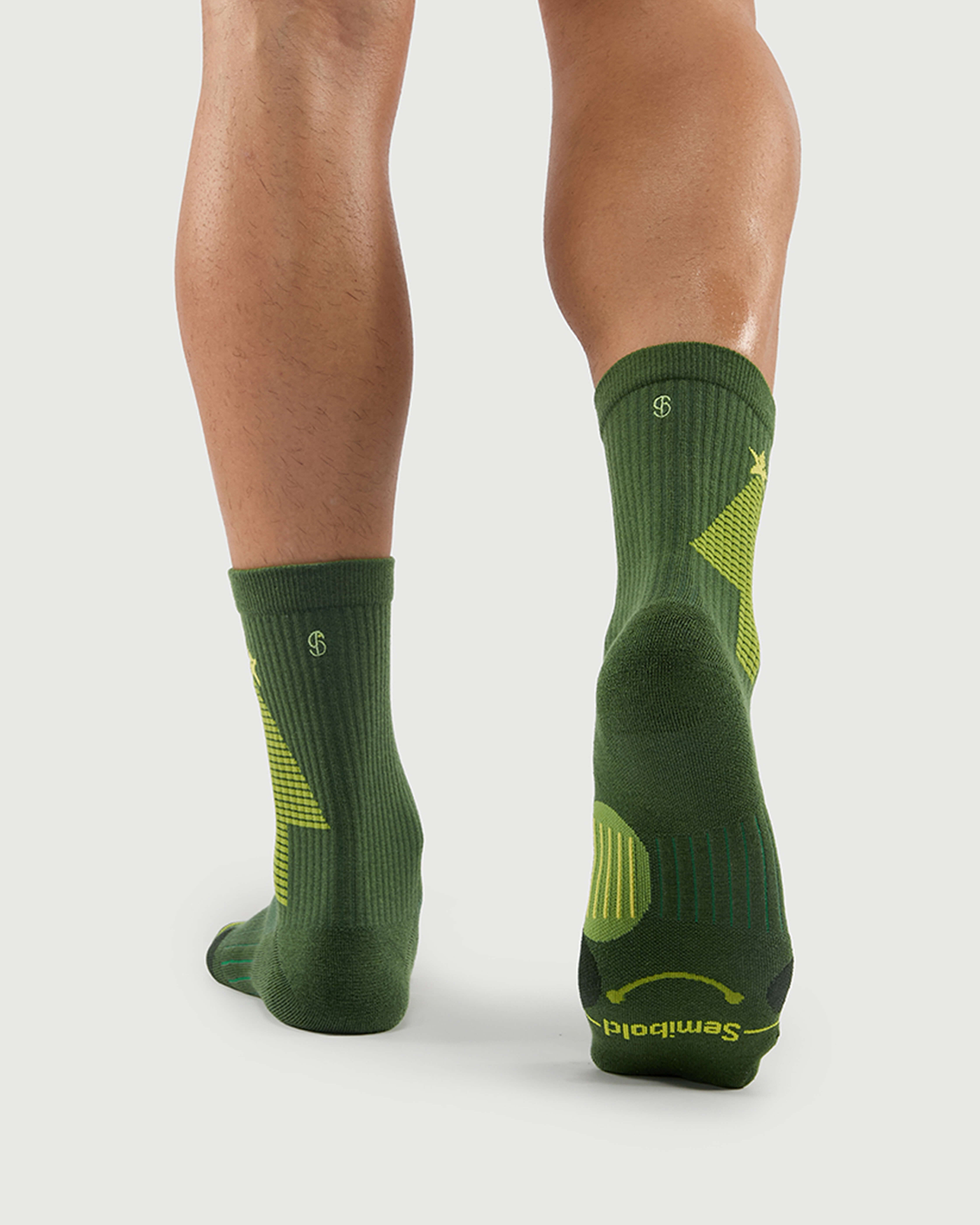 Back view of Starry Pine Merino wool socks on a model, featuring the distinctive yellow tree design and reinforced heel protection.