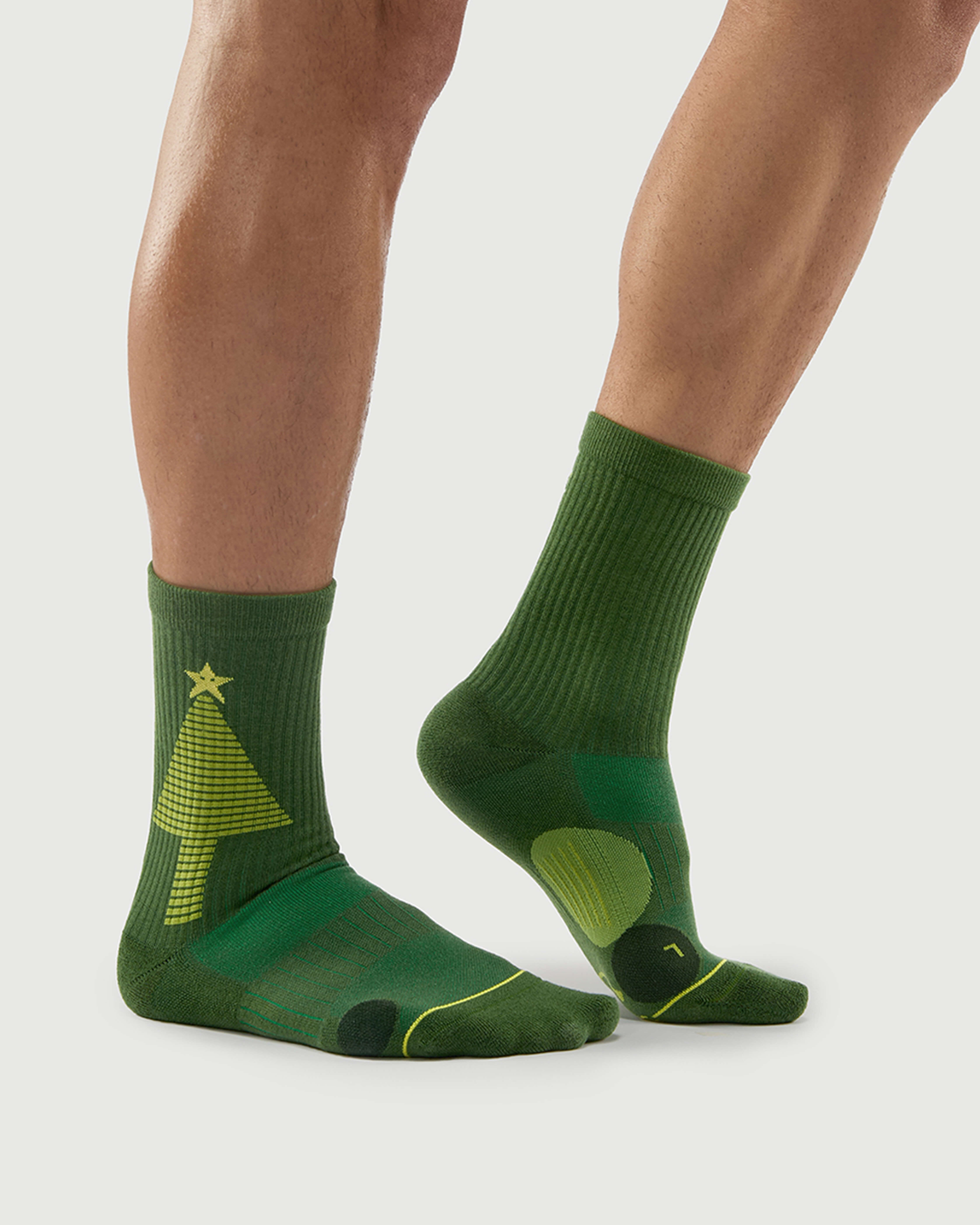 Close-up of a model wearing Starry Pine Merino wool socks, highlighting the light green Christmas tree and star pattern on the side.