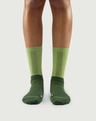 Front view of Crafty Otter socks on a model, featuring dark green and light green two-tone panels.