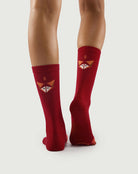 Back view of red Devoted Fox socks on a model, showing the fox face and arch support sole.