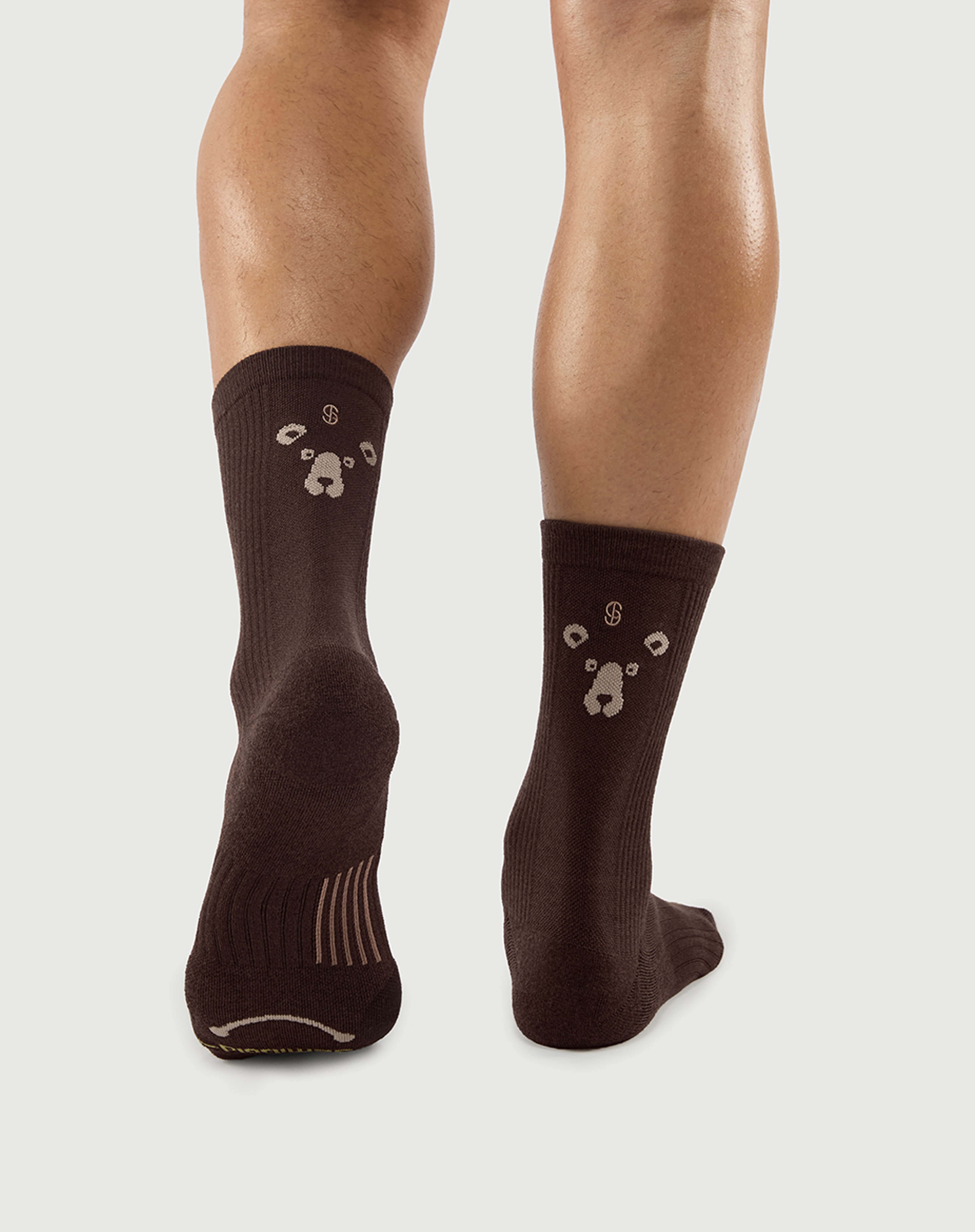 Back view of brown Humble Bear socks on a model, showcasing the bear face pattern on the heel.