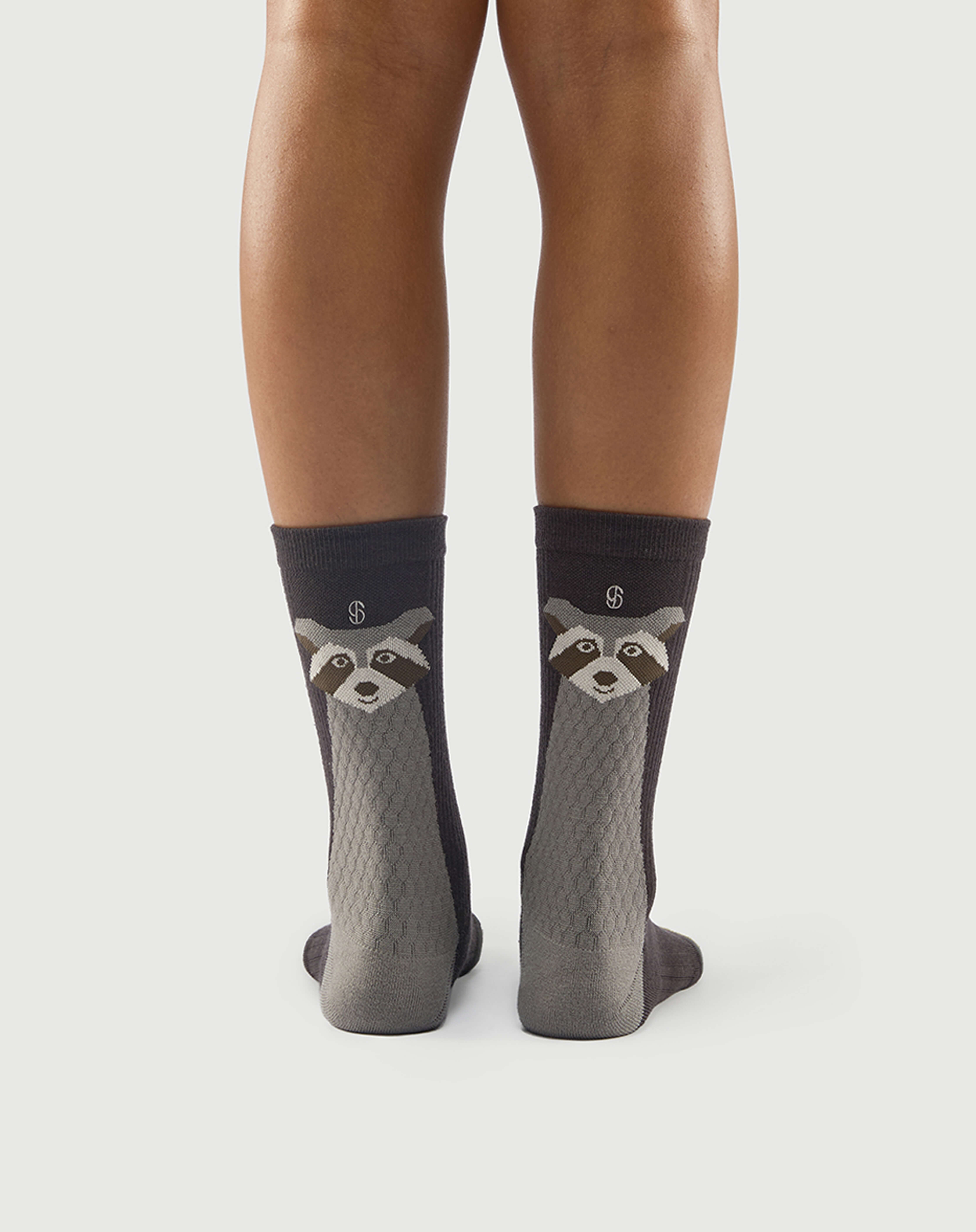 Model wearing grey and black Scrubby Raccoon socks, highlighting the raccoon character on the back.