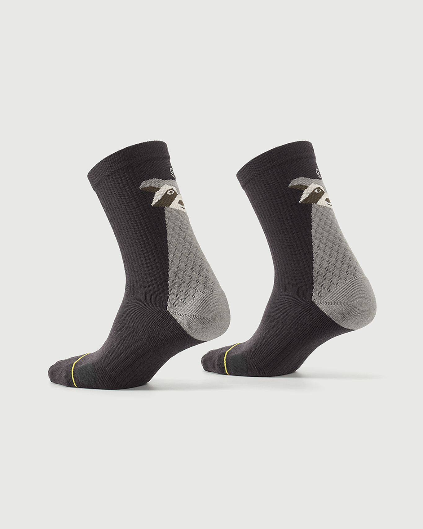 Grey Scrubby Raccoon socks on a foot form, displaying the side and rear character design.