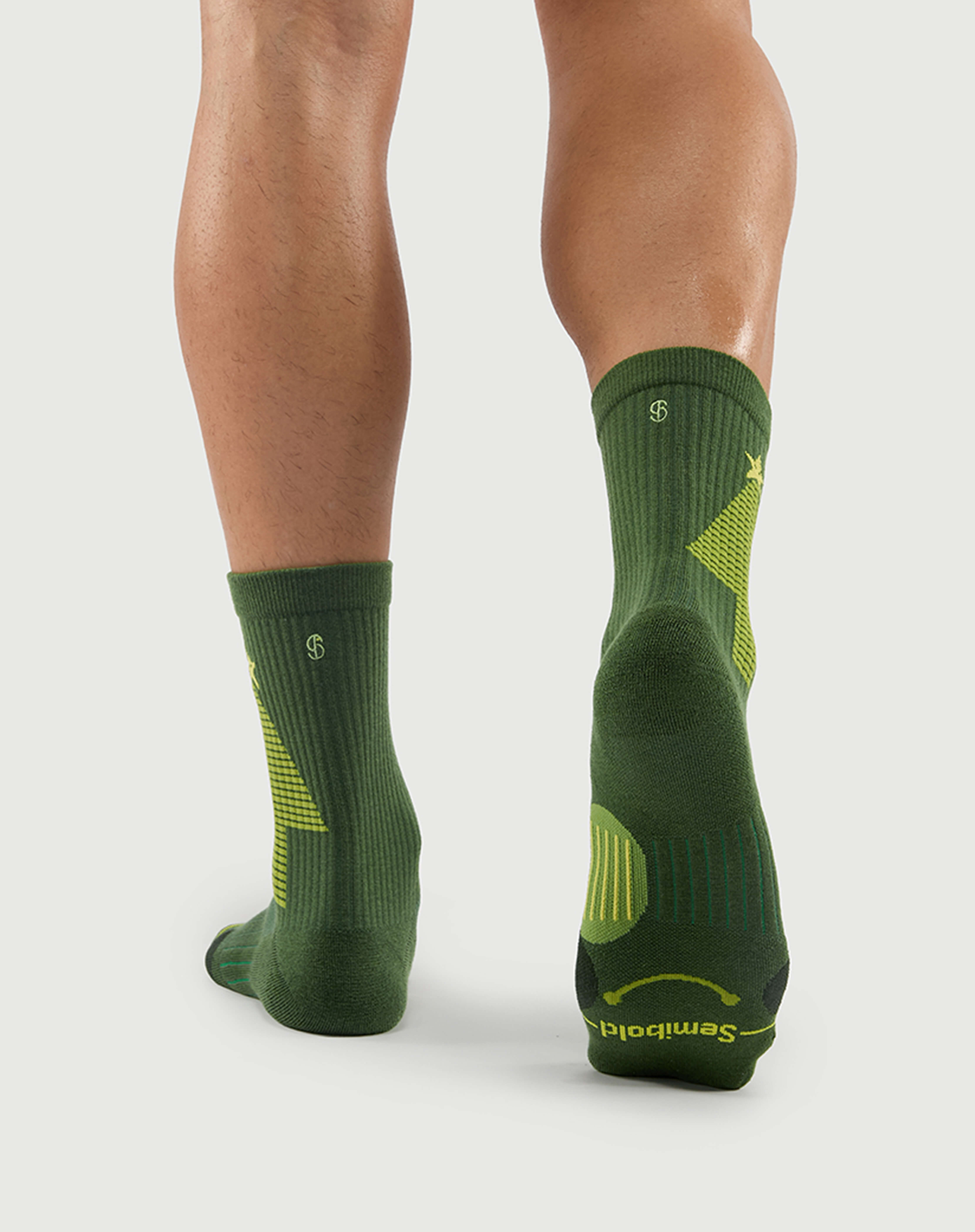 Back view of Starry Pine Merino wool socks on a model, featuring the distinctive yellow tree design and reinforced heel protection.